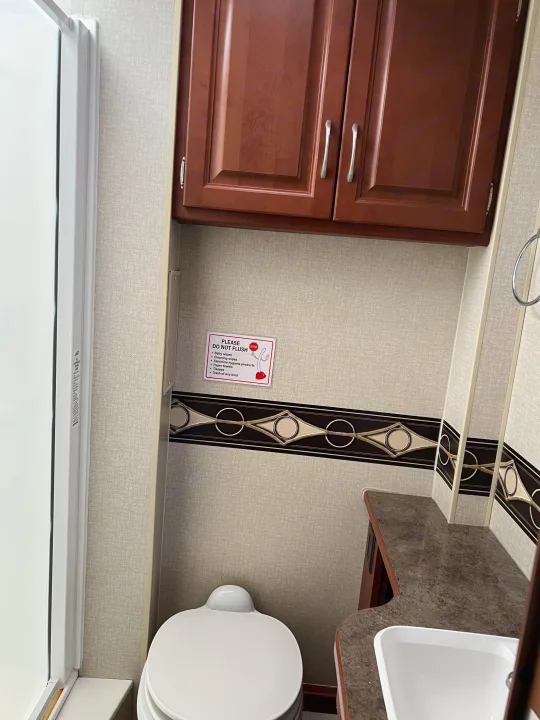 RV rental bathroom: compact space with toilet, sink, shower, and a crucial "Do Not Flush" sign.. Winnebago Minnie Winnie 2015