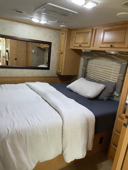 Cozy bedroom interior of an RV rental, with a comfortable bed, overhead cabinets, and a mirror.. Damon Corporation Challenger 2009