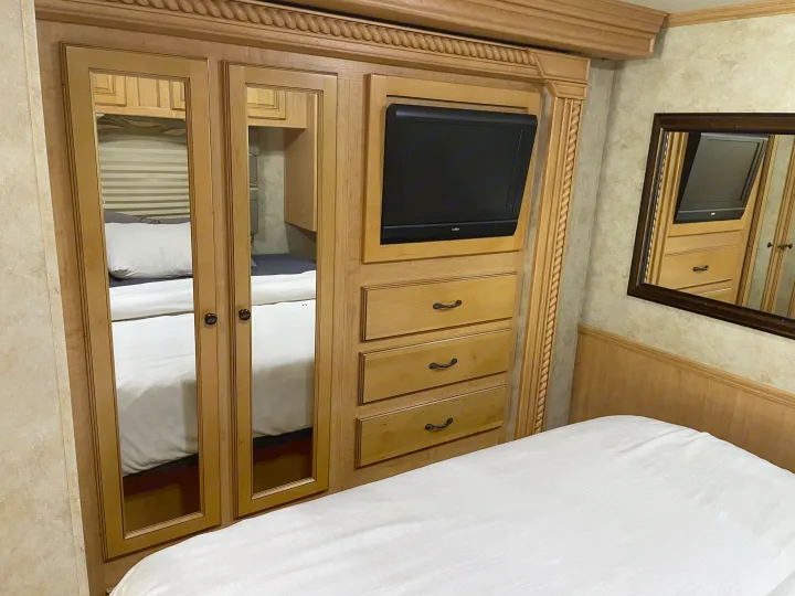 Inside an RV rental: a cozy bedroom with a wooden mirrored wardrobe, built-in TV, and inviting bed.. Damon Corporation Challenger 2009