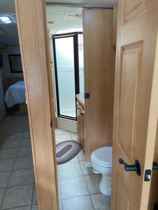 Peek inside an RV rental: A well-appointed bathroom featuring a shower, toilet, and vanity, with a bedroom visible beyond.. Damon Corporation Challenger 2009