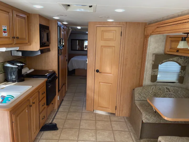 RV rental living space: Explore the bright kitchen, dining booth, and bedroom hallway of this cozy RV.. Damon Corporation Challenger 2009