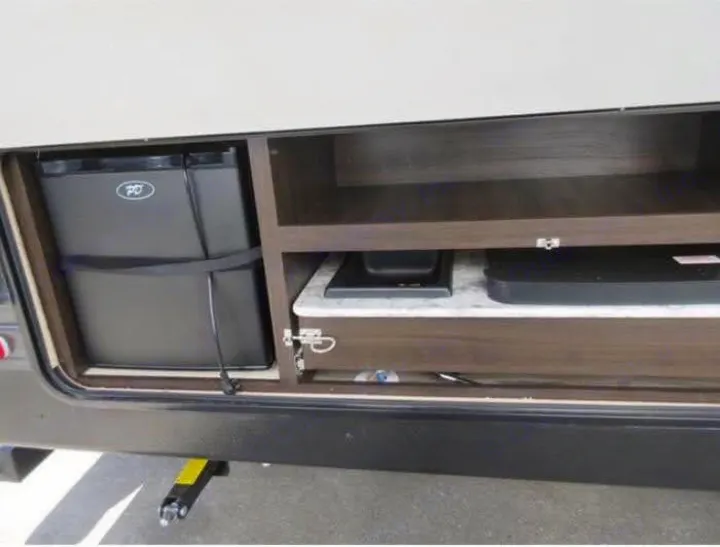 Explore this RV rental's outdoor kitchen, featuring a mini-fridge, cooktop, and storage for your adventures.. Keystone RV Springdale 2019