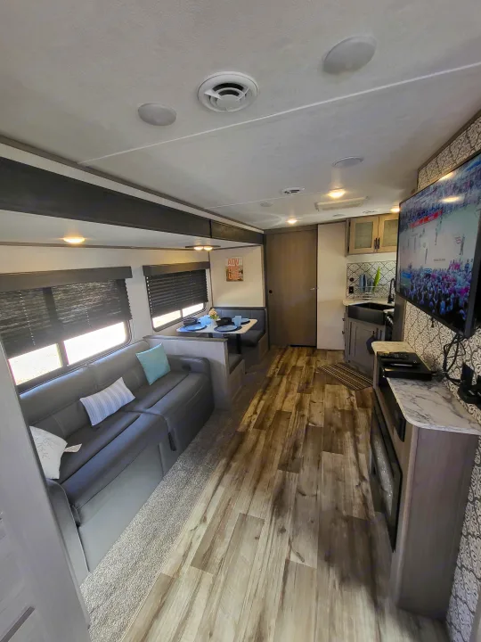 Explore this modern RV rental's inviting interior: sleek kitchen, comfortable sofa, and dinette set for your adventures.. Dutchmen 285BH 2022
