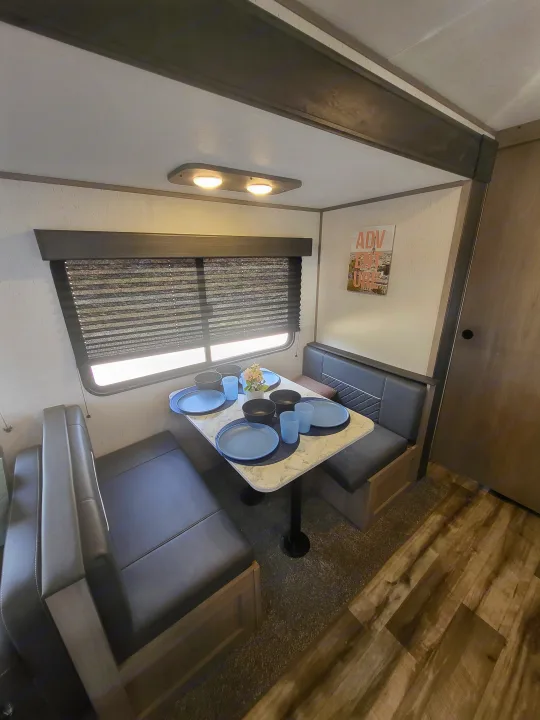 RV rental: Modern dinette featuring dark booth seating, marble-top table set with dishes, and large window.. Dutchmen 285BH 2022