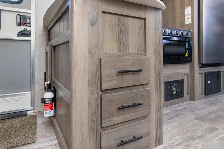 RV rental interior features a kitchen island with storage, stove, and a conveniently mounted fire extinguisher for safety.. Gulf Stream 268BHS 2023
