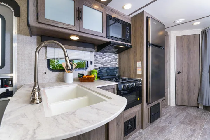 Spacious RV rental kitchen featuring a sink, microwave, stove, and refrigerator, ideal for road trip cooking.. Gulf Stream 268BHS 2023