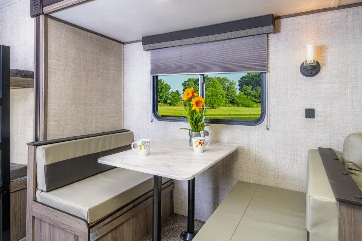 Enjoy this cozy RV rental dinette with nature views. Perfect for meals, the area features a table, bench seating, and bunk beds.. Gulf Stream 268BHS 2023
