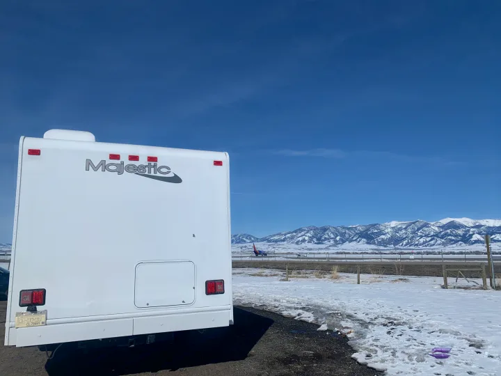 White Majestic RV rental with snow, distant mountains, and a Southwest Airlines plane on a runway.. Thor Freedom Elite 2019