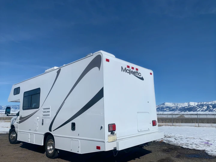 White Majestic RV rental, ready for adventure! Parked in a snowy landscape with mountains under a clear blue sky.. Thor Freedom Elite 2019