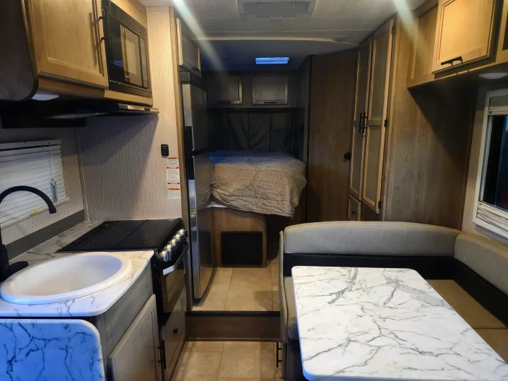 Modern rv rental interior with kitchen, bed, dinette, and light wood cabinetry for comfortable living on the road.. Coachmen Other 2022
