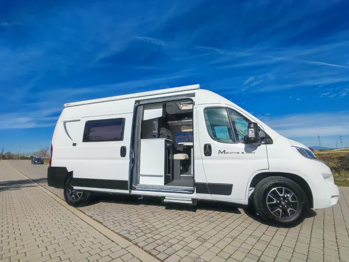 Sunny view of a white Menfys S Max camper van, side door open to interior, parked on paving. Ideal for an RV rental trip.. McLouis MENFYS 3 MAXI 2026