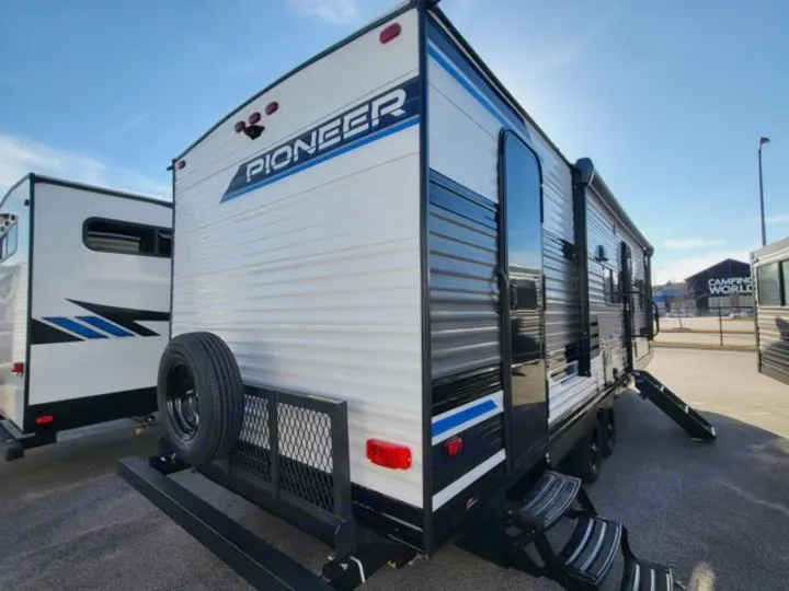 This white and black Pioneer travel trailer, perfect for an RV rental, is seen from the rear with a spare tire and extended side steps.. Heartland Pioneer BH270 2023