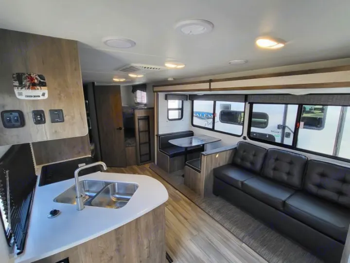 Spacious RV rental interior: kitchen, living area with sofa, dinette, bunk beds, and large windows.. Heartland Pioneer BH270 2023