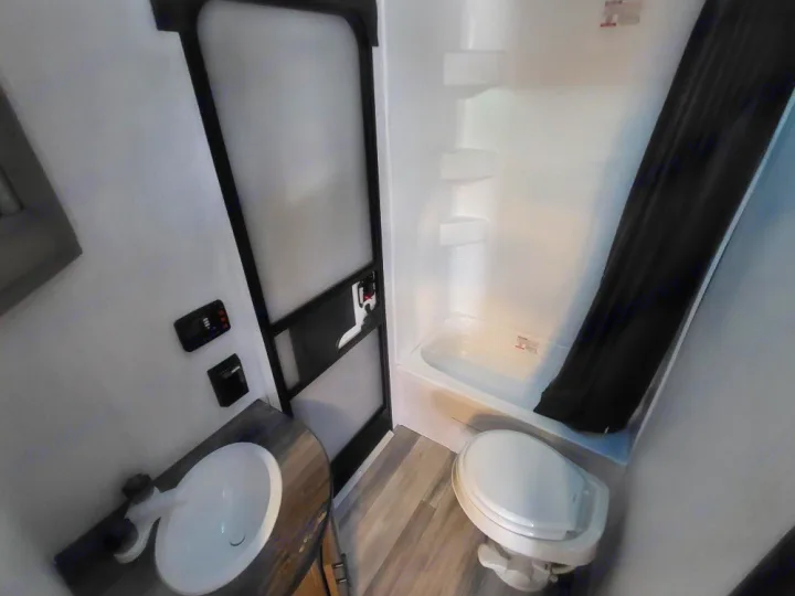 Functional bathroom in an RV rental, featuring a compact sink, toilet, and shower/tub combo.. Heartland Pioneer BH270 2023