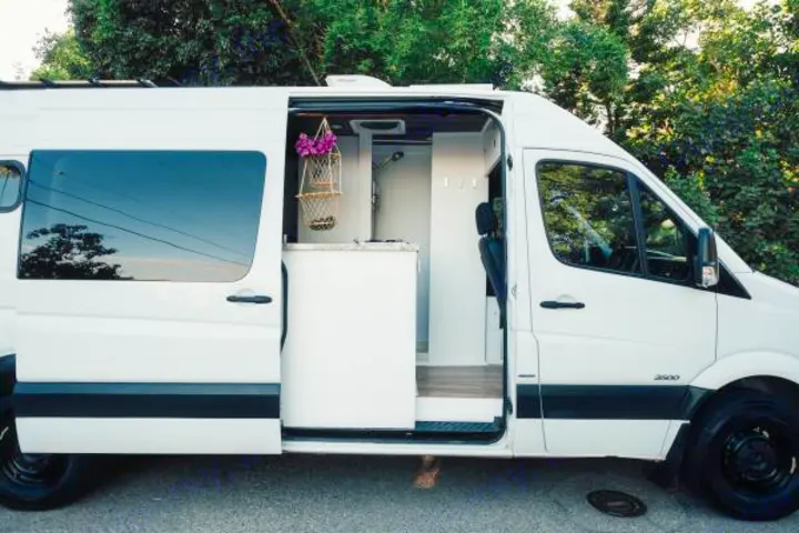 White camper van, ideal for rv rental, showing its custom interior with compact kitchen, shower, and decor.. Mercedes-Benz Sprinter 2013