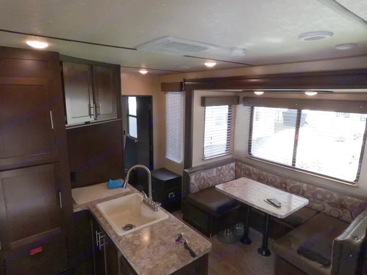 Spacious RV rental interior with a dark wood kitchen, sink, and a comfortable L-shaped dinette. Ideal for your next trip.. Forest River XLR Boost Toy Hauler 2018