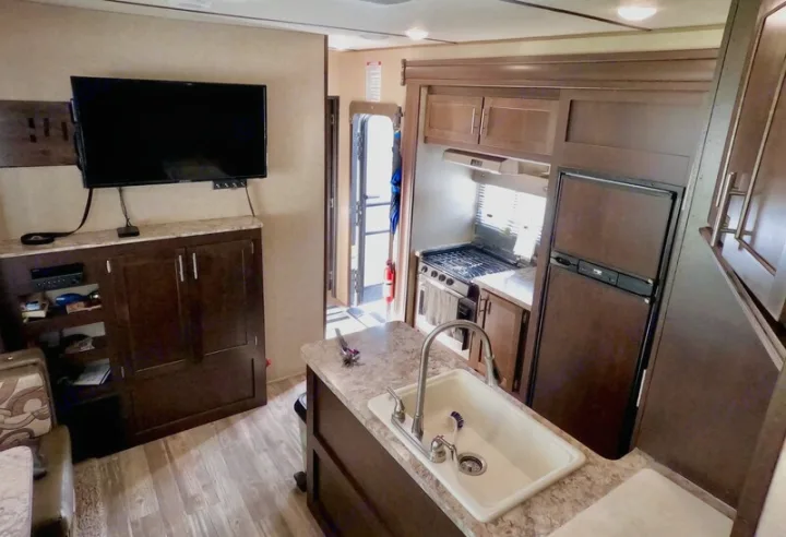 Step inside this RV rental! Features a living area with TV, and a compact kitchen including a sink, stove, and fridge.. Forest River XLR Boost Toy Hauler 2018