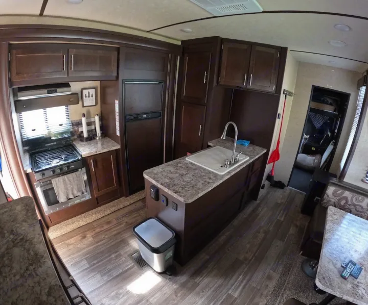 RV rental interior: A functional kitchen area with stove, sink, fridge, and dining space in a cozy mobile home.. Forest River XLR Boost Toy Hauler 2018