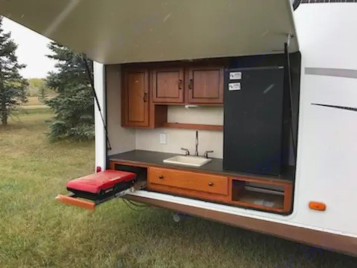 This RV rental features an outdoor kitchen with a sink, mini-fridge, and pull-out grill for convenient outdoor cooking and camping.. Coachman Freedom Express 2011