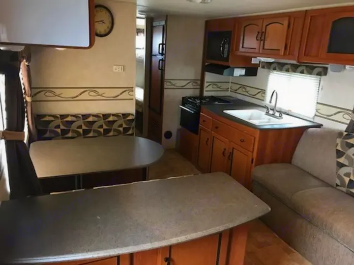 Functional RV rental interior with kitchen, dining booth, and sofa living area, perfect for travel.. Coachman Freedom Express 2011