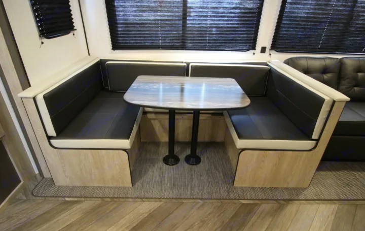 This RV rental features a comfortable U-shaped dinette with black and white seating and a table, ideal for dining in the RV interior.. Heartland RVs Prowler 2022