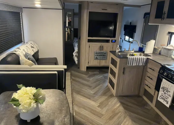 Explore this comfortable RV rental interior, featuring a full kitchen, cozy living area, and private bedroom access.. Heartland RVs Prowler 2022