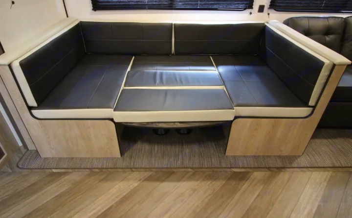 This RV rental showcases a modern U-shaped dinette with black and light-colored cushions, converting to a bed.. Heartland RVs Prowler 2022