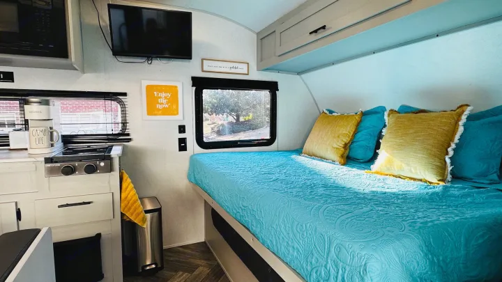 Bright RV rental camper interior: cozy bed, full kitchen with stove, microwave, and sunny window views.. Forest River Wildwood 2021