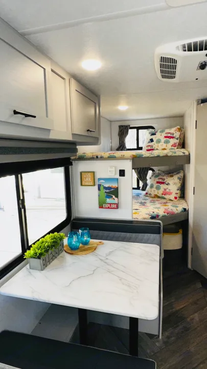 RV rental interior with a cozy dinette, modern cabinets, and comfy bunk beds, great for family trips.. Forest River Wildwood 2021
