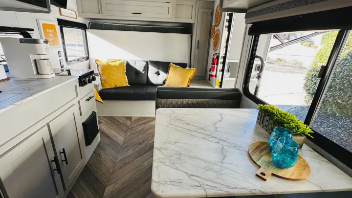 Modern RV rental interior: kitchen, dining, comfy sofa with yellow pillows. Ready for travel!. Forest River Wildwood 2021