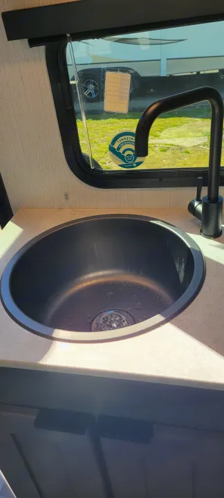 Inside an RV rental: a compact kitchen with a modern black sink, faucet, and window view.. Heartland RVs Mallard 2022