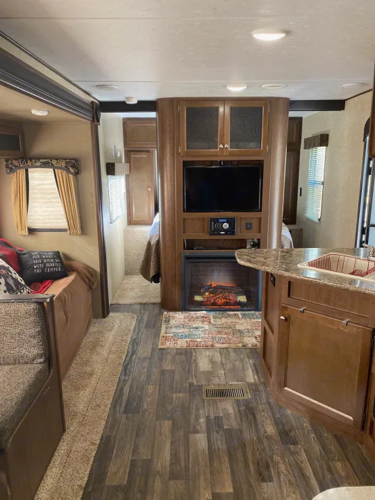 RV rental interior: living area, kitchen, fireplace, and a glimpse of the bedroom for comfortable travel.. Keystone RV Hideout 2016