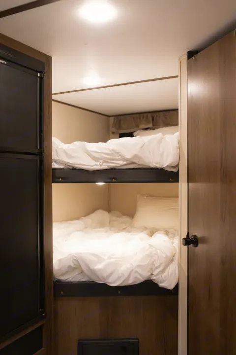 Our RV rental features cozy bunk beds with white bedding, plus a fridge and storage, perfect for your adventure.. Avenger ATI 2020