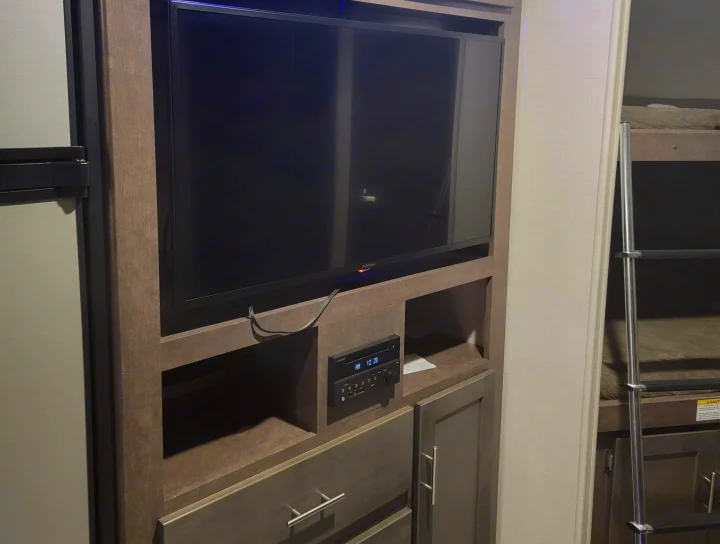 Inside an RV rental: Entertainment center with TV, stereo system, and adjacent bunk beds.. Crossroads RV Sunset Trail Super Lite 2019