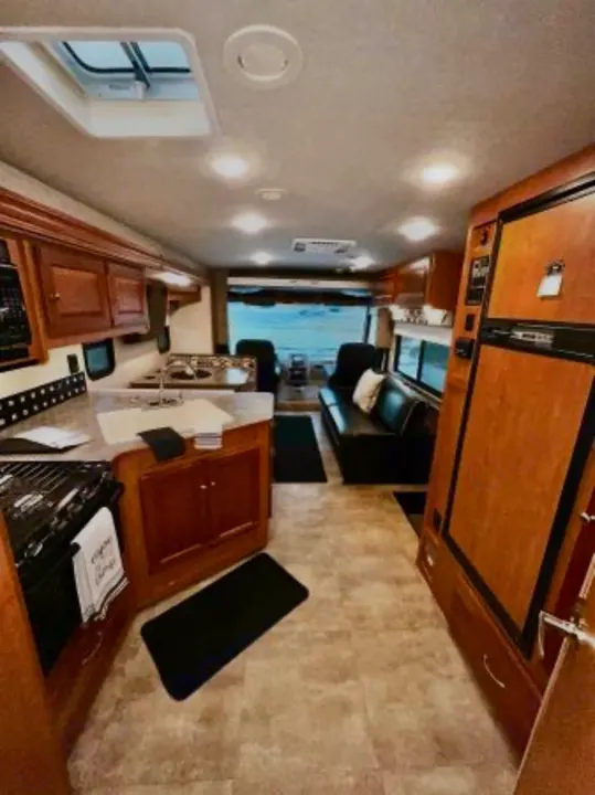 Spacious rv rental interior featuring a full kitchen, living area with a sofa, and driver's cockpit.. Winnebago Sunstar 2016