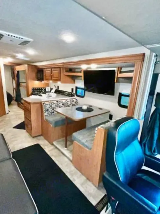 Inside this **RV rental**, find a dining booth, kitchen counter, wall-mounted TV, and cozy seating, including a prominent blue chair.. Winnebago Sunstar 2016