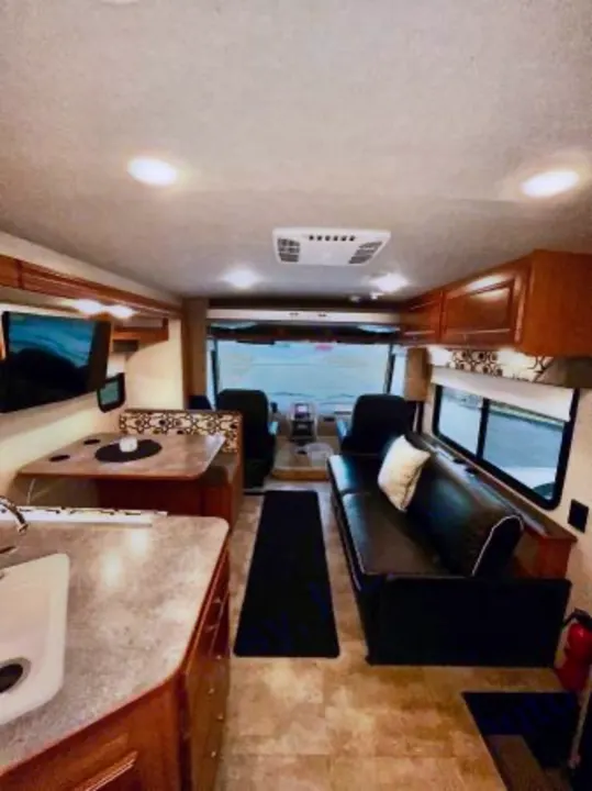 Spacious RV rental interior with kitchen, dining area, sofa, and cockpit visible, offering comfortable living space.. Winnebago Sunstar 2016