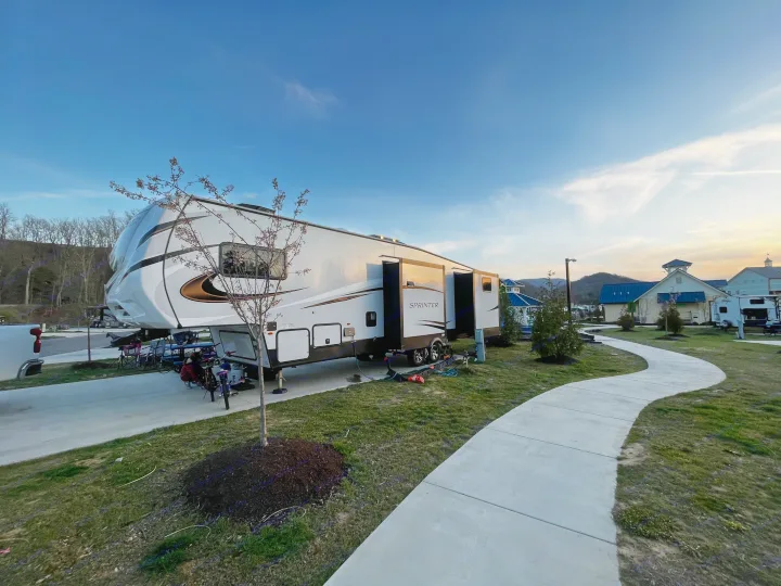 Spacious fifth-wheel RV rental parked at a scenic campground with slide-outs extended, a path, and mountains.. Keystone Sprinter 2023