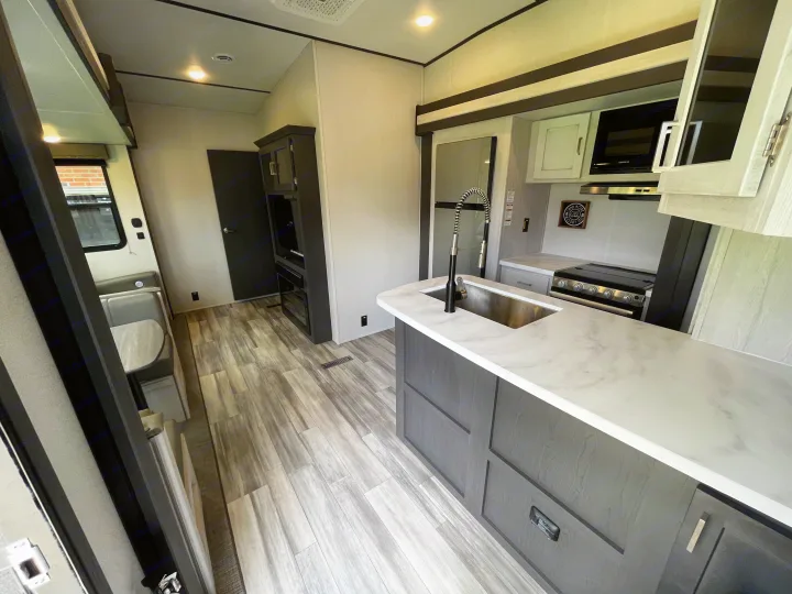 Modern RV rental interior: well-equipped kitchen with island, stove, microwave, plus a cozy dinette area.. Keystone Sprinter 2023