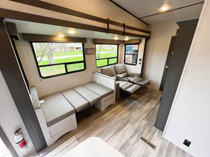 This RV rental's interior boasts a convertible dinette, comfy recliners, and wood-look flooring, offering a cozy living space.. Keystone Sprinter 2023