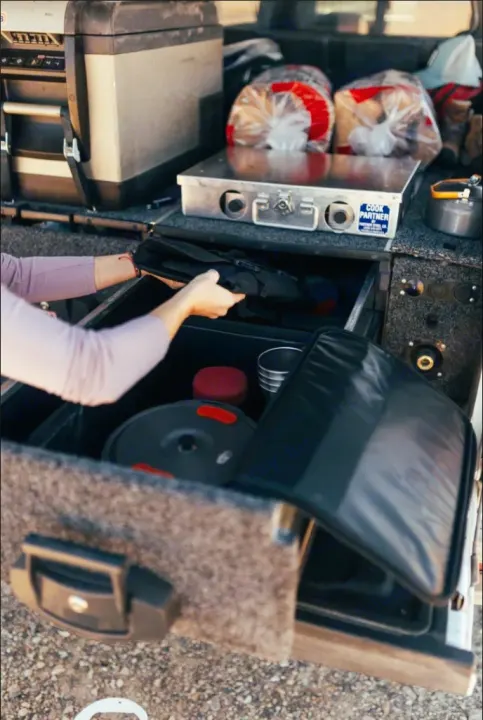 An RV rental's organized camp kitchen: a portable stove, fridge, and smart drawer storage for overland cooking.. Jeep Gladiator 2022