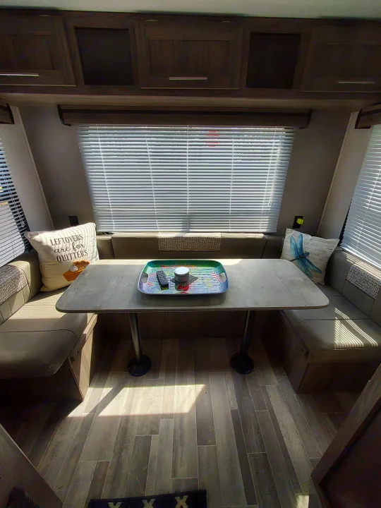 Bright RV rental interior: dinette, ample cabinets, blinds, and wood-look flooring. Cozy travel home.. Crossroads RV Zinger Lite 2022