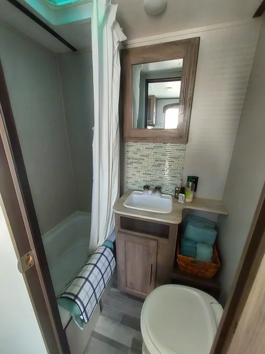 RV rental interior: View of a compact, clean bathroom with a sink, mirror, toilet, and shower area.. Crossroads RV Zinger Lite 2022