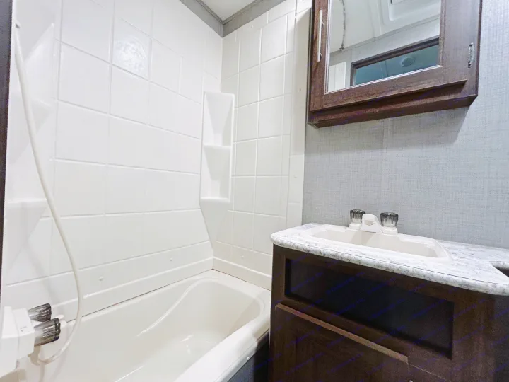 This RV rental features a functional bathroom with a compact bathtub/shower, tiled walls, a vanity with sink, and mirrored medicine cabinet.. Zinger ZR29OKB 2018