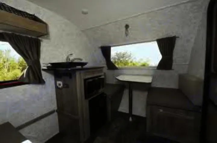Inside an RV rental: Features a compact kitchen with sink, microwave, and a cozy dinette. Ideal for camping & road trips.. Prolite 12 V 2019