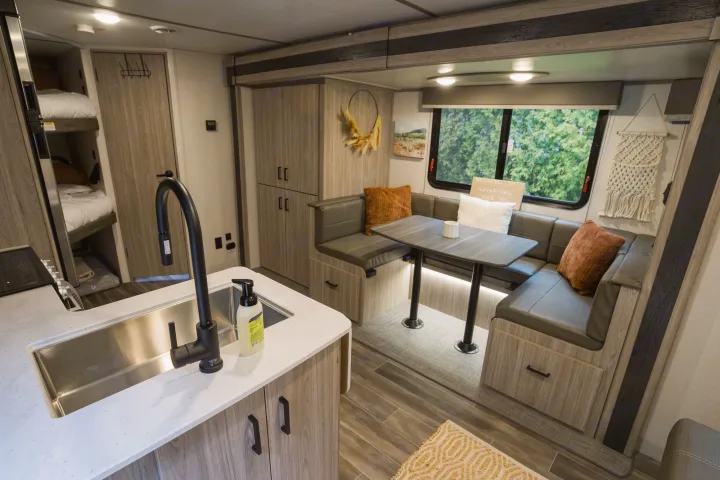 Spacious **rv rental** interior featuring a modern kitchen, U-shaped dinette, and cozy bunk beds. Perfect for family adventures.. Keystone RV Passport SL 2022