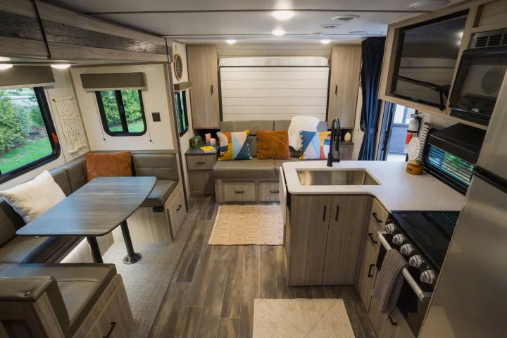Inside a bright rv rental, explore a modern kitchen, comfortable dining nook, and a versatile sofa/bed area.. Keystone RV Passport SL 2022