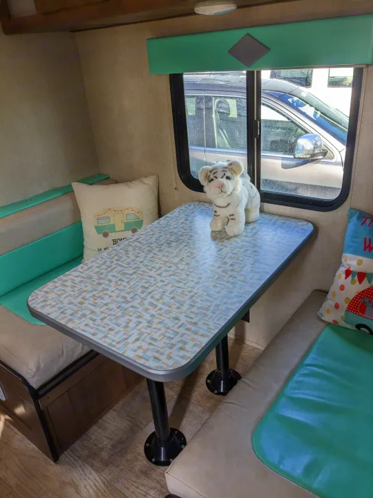 Cozy RV rental dinette with patterned table, plush benches, and a friendly stuffed tiger, ready for your next adventure.. Gulf Stream Capri 2019