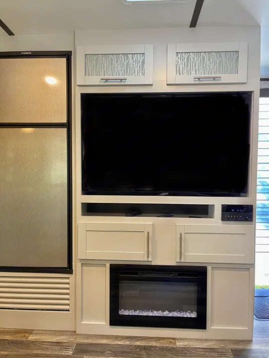 Modern RV rental interior featuring a Dometic refrigerator, entertainment center with TV, and an electric fireplace.. Keystone RV Bullet Premier Ultra 2020