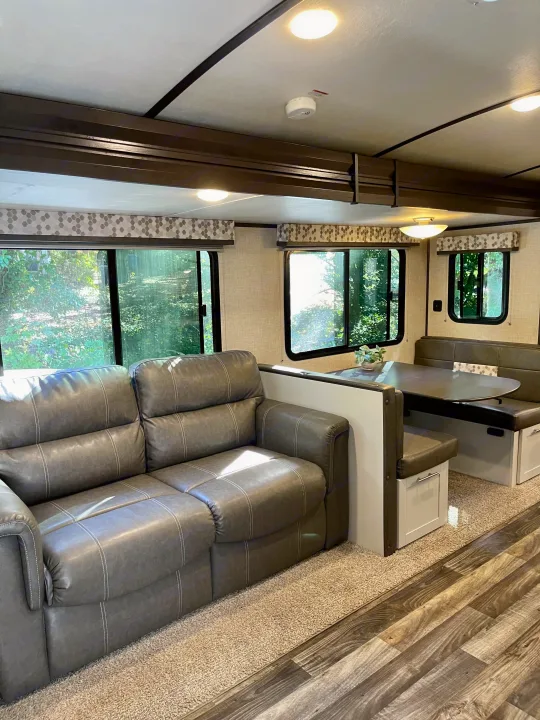 Enjoy this RV rental's cozy living space: gray sofa, dinette with storage, and large windows with natural light.. Keystone RV Bullet Premier Ultra 2020